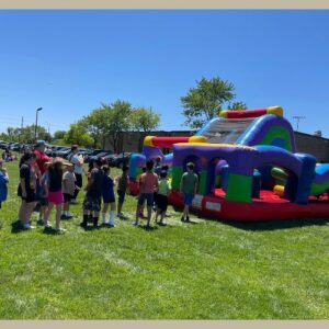 students waiting in line to jump on a colorful bouncy inflatable