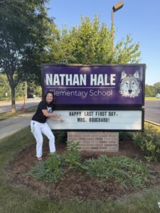 Mrs. Bouchard standing in front of the Hale Marquee sign that says "Happy Last First Day Mrs. Bouchard"